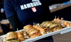 Picture: Person with blue Hamburg T-shirt holding a tray with sandwiches.
