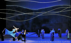Picture: On the stage of the State Opera with a blue background scene with singers and ballet couple.